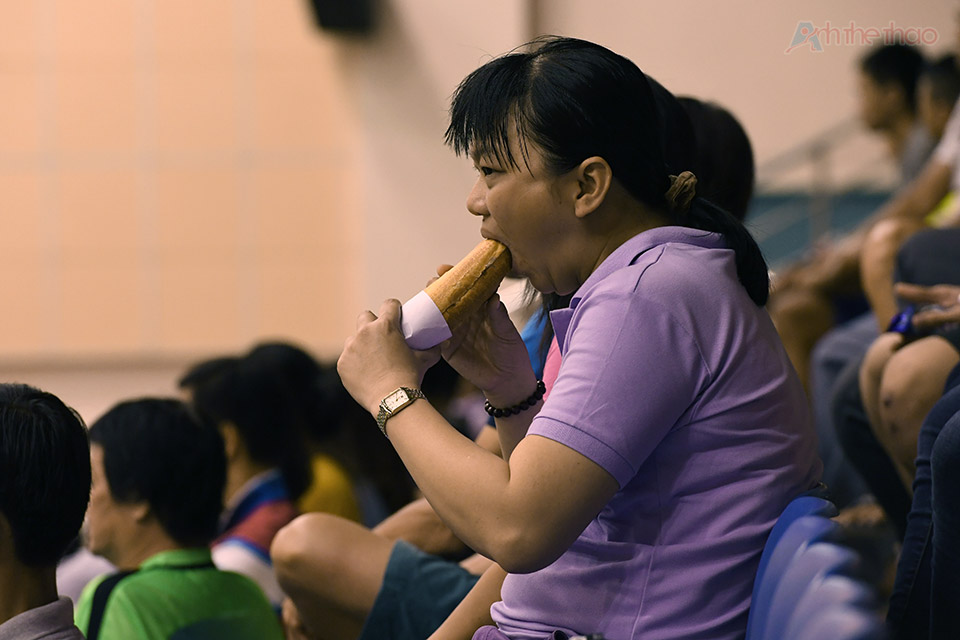 Khán giả nữ tranh thủ ăn chiều trong khi xem trận đấu 